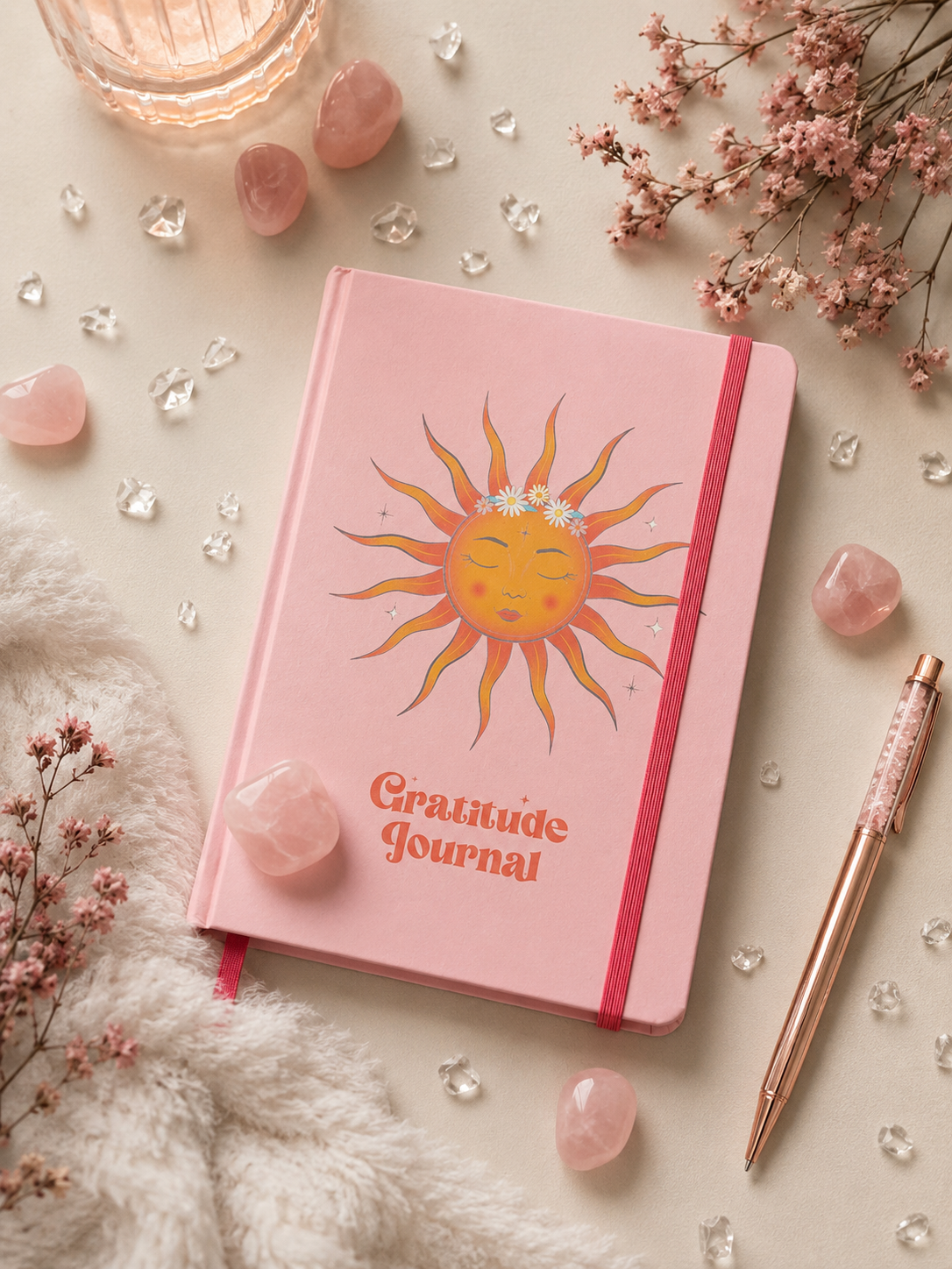 Offenes spirituelles Dankbarkeitstagebuch mit Rosenquarz-Stift auf einem dekorativen Flatlay mit Rosenquarz-Kristallen und Trockenblumen.